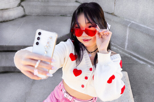 Trendy Gen Z chinese girl taking selfie with smartphone