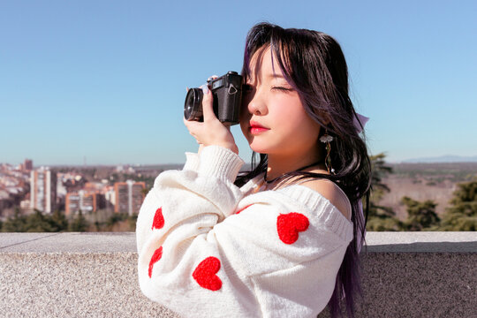Stylish chinese girl with camera overlooking cityscape