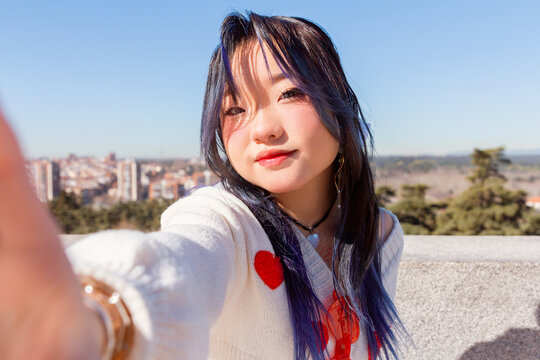 Trendy Gen-Z chinese girl taking a selfie with urban background