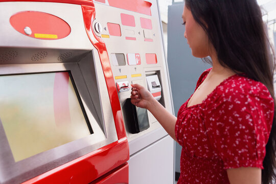 Woman in red dress using a ticket vending machine