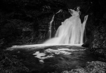 A black and white portrayal of the Rio Mundo Waterfall's vigorous cascade, creating a striking contrast with the surrounding rocks