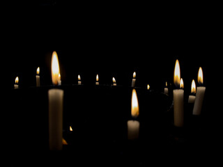 row of isolated candles in the dark, black background