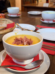 bowl of creamy soup served with bacon ham on table
