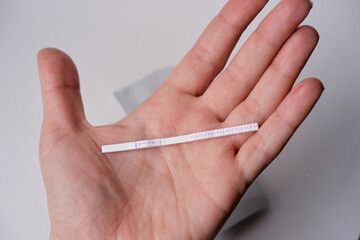 a woman holds a pregnancy test in her palm. pregnancy test close up