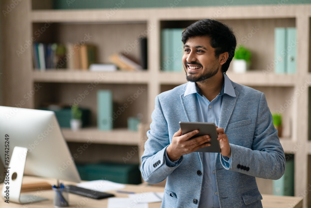 Leinwandbilder happy indian programmer man using tablet standing in modern office