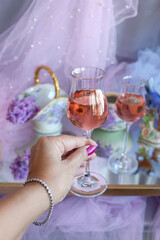 A glass of pink wine in the girl's hand in close-up