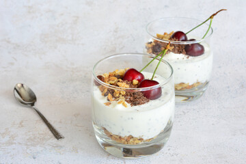 chia pudding with granola, chocolate and cherry in drinking glass 