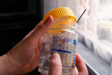 Woman checking label of empty peanut butter jar. Ingredient control, nutritional values, fat,...