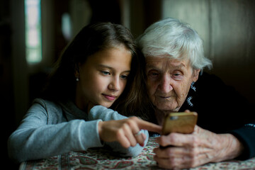 A girl teaches her grandmother how to use her smartphone.