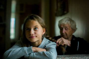 A grandmother braids her disgruntled granddaughter's hair.