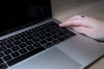 Young Caucasian woman's hand pressing the enter button on a laptop keyboard.
