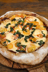 Pizza with mozzarella and provolone cheese, garlic and cherry tomatoes on the restaurant wooden...