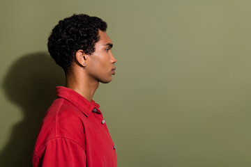 Photo of serious confident guy wear red shirt looking empty space isolated khaki color background