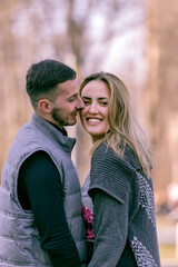 Fototapeta premium Happy couple in love. Stylish man with a beard and a beautiful girl on the autumn sunny day kissing. Portrait of a happy young couple enjoying a day in the park together .