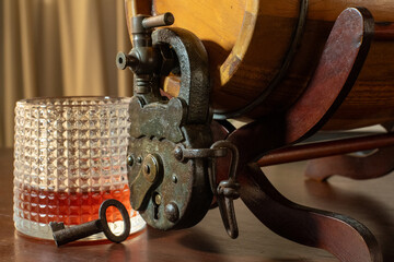 Barrel of liquor with open padlock and key next to a poured glass.
