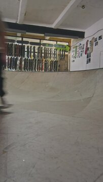 Vertical shot of skateboarding crew skating bowl and passing camera one by one while training at skatepark