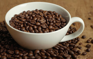 Fototapeta premium A coffee cup full of roasted coffee beans. Grains scattered around the cup.