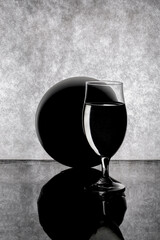 Still life with a glass of liquid and a large ball