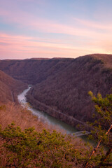 Vertical view of winding river in canyon flowing through dense tree covered mountains at New River Gorge National Park during sunset