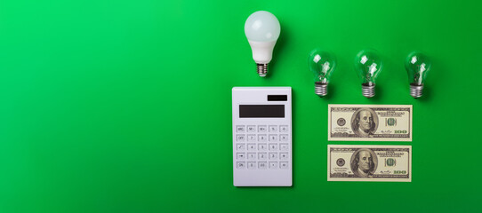 White calculator and incandescent lamps or LED bulb on green background. Concept showing the payment money of electricity bills. savings electricity. Reducing the payment of utility bills..