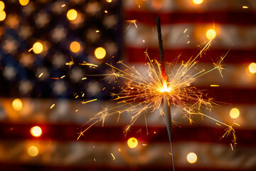 Lit sparkler in front the American Flag for 4th of July celebration