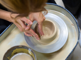 Fototapeta premium A close-up of a craftsman making an object out of clay on a potter's wheel. Handmade, hobby, hobby, selective focus, top view