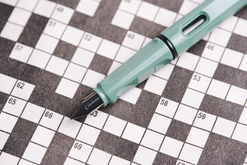 Emerald colored fountain pen lies on crosswords. Hobbies and mental memory.