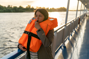 woman wearing an orange life jacket blows a whistle 