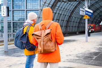 Passengers with backpacks wait for train at station, Berlin Hauptbahnhof of Deutsche Bahn, concept...