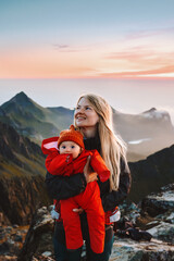 Mother walking with infant baby in mountains outdoor family travel lifestyle scandinavian woman with child hiking in Norway summer vacations in Lofoten islands Mothers day holiday - obrazy, fototapety, plakaty