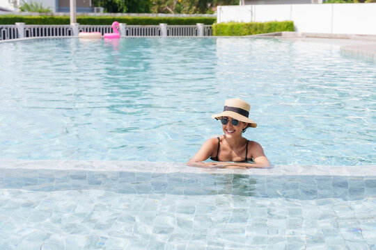Woman relaxes in a pool,  smile radiant under sun, enjoying a serene moment of leisure and relaxation. Basking in sunlight,  cheerful female enjoys refreshing water of pool, exuding vacation vibes