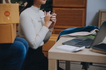 Asian SME business women use laptop computer checking customer order online shipping boxes at home....