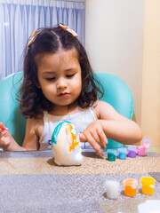 Niña feliz y concentrada jugando con pinturas y temperas