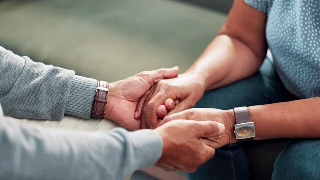 Counseling, holding hands and senior couple in living room together with love, comfort and prayer in home. Marriage therapy, old man and woman on sofa with care, kindness and faith in retirement.
