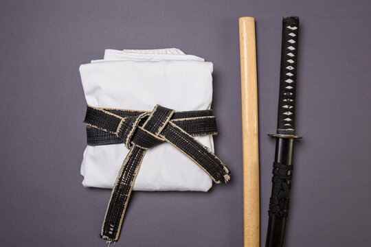 A Set of Traditional Martial Arts Items and Clothing on a Gray Background &mdash; White Gi with Black Belt in Center
