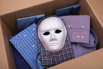 White mask and various shirts in an open cardboard box, concept on the theme of smuggling