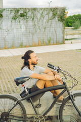 Obraz premium young latin man resting pensively on a bench next to his bicycle