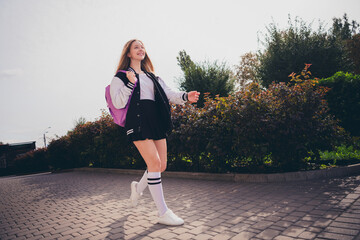 Photo of adorable positive girl dressed bomber short skirt backpack hurrying school enjoying warm...