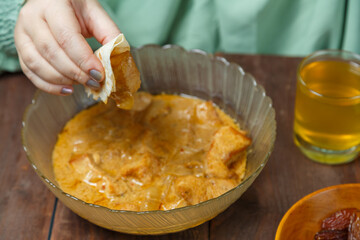 A Muslim woman's hand at the table takes lamb during Ramadan iftar