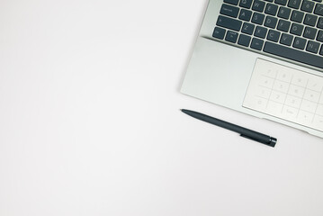 Top view of laptop and pen on white background