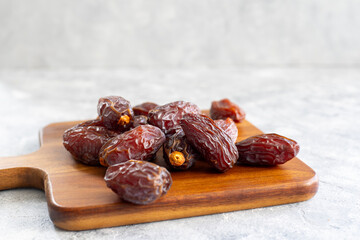 Organic pile of medjoul dates on a wood serving board. Ramadan food. 