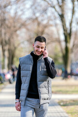 Handsome man talking on the mobile phone outdoor with green background