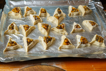 Sweet gomentashi cookies, not baked, are placed on foil on a baking sheet