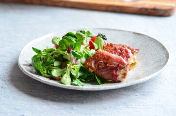 beautiful background of food served on a rustic plate, italian cuisine, grilled veal meat with parma ham and sage, mixed salad, close up view,
