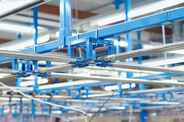 A metal roller rail in a textile factory industrial setting. Metal oil hangers on metal rollers....