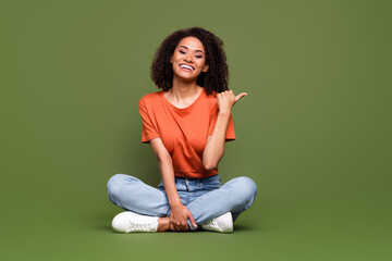 Full length photo of sweet pretty woman wear orange t-shirt showing thumb empty space isolated green color background