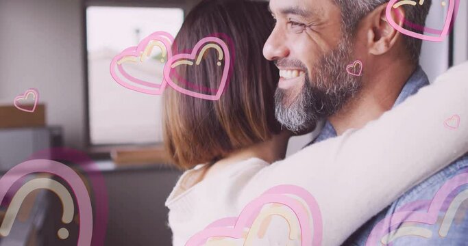 Animation of hearts over diverse couple embracing and smiling at home