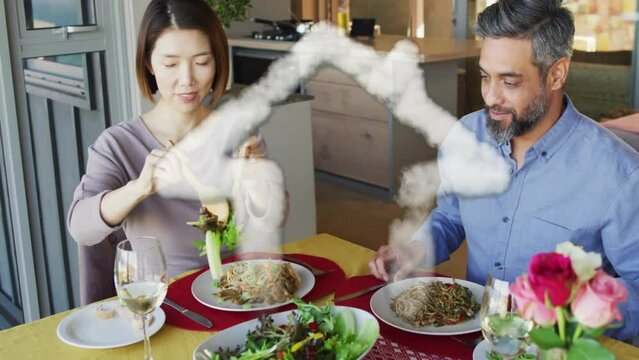 Animation of house shape over diverse couple eating dinner at home