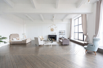 Modern luxury stylish apartment interior in pastel colors. a very bright room with huge windows filled with daylight. white walls, wooden parquet floors and a dark marble fireplace