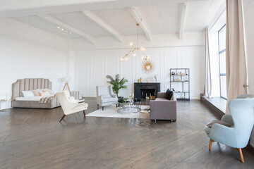 Modern luxury stylish apartment interior in pastel colors. a very bright room with huge windows filled with daylight. white walls, wooden parquet floors and a dark marble fireplace